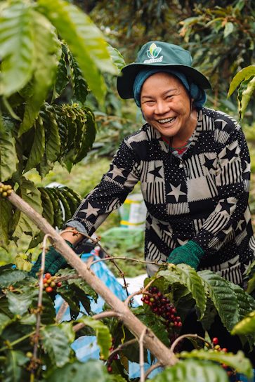 a smiling woman picking berries from a tree