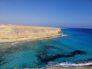 A serene coastline with turquoise waters and rocky cliffs under a clear sky.