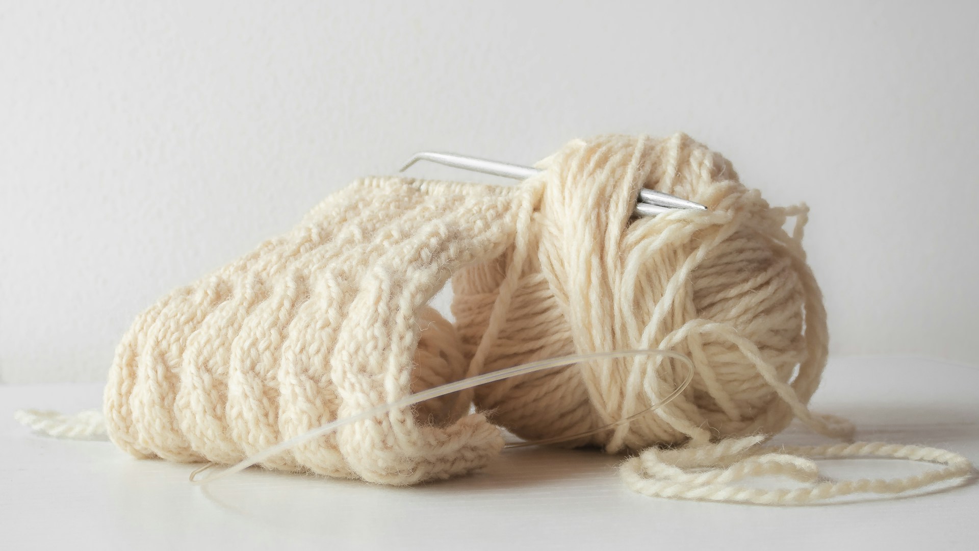 a ball of yarn and a knitting needle on a white surface