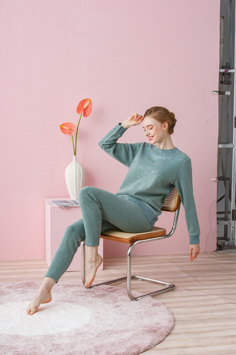 a woman sitting on a chair in a pink room