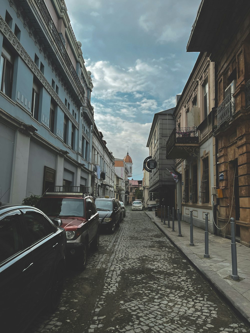 a street lined with parked cars next to tall buildings