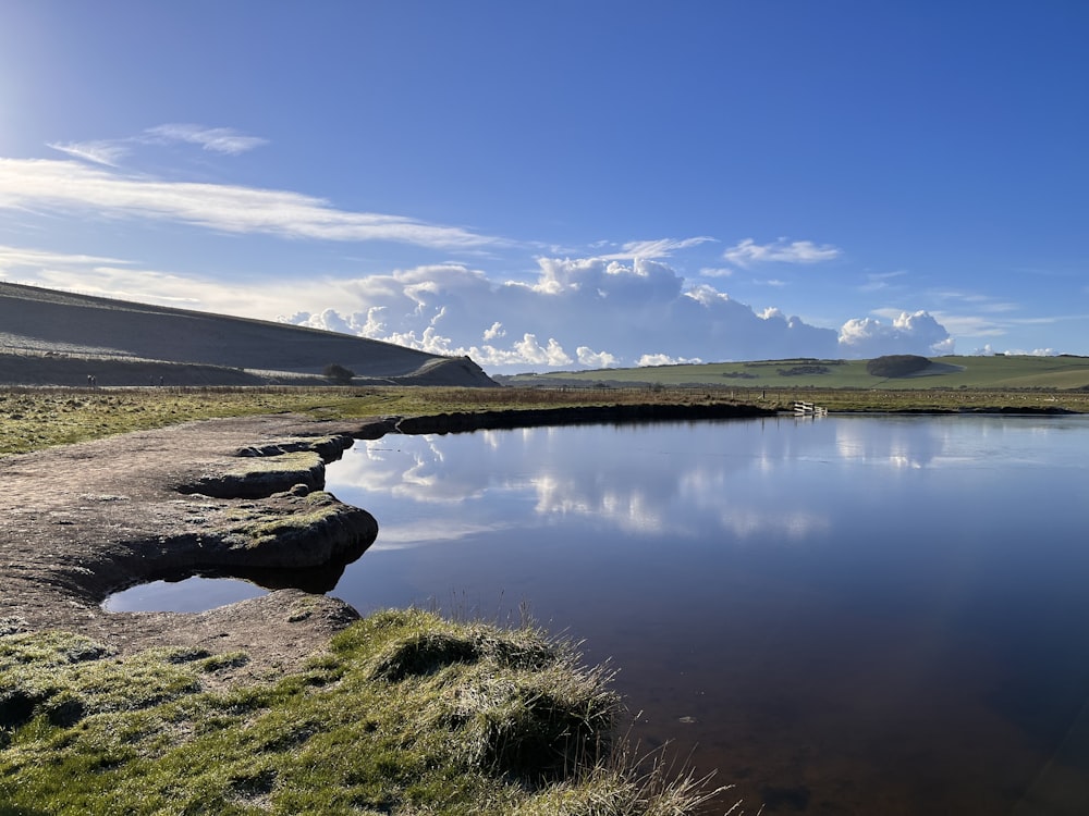 a large body of water surrounded by a lush green field