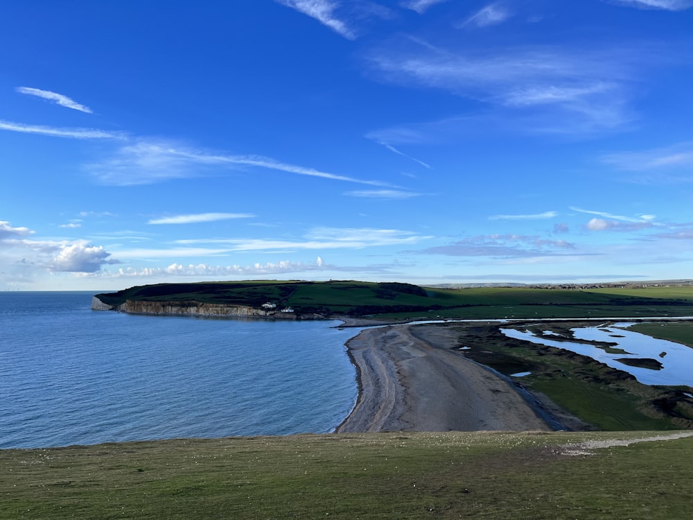 a large body of water sitting next to a lush green hillside