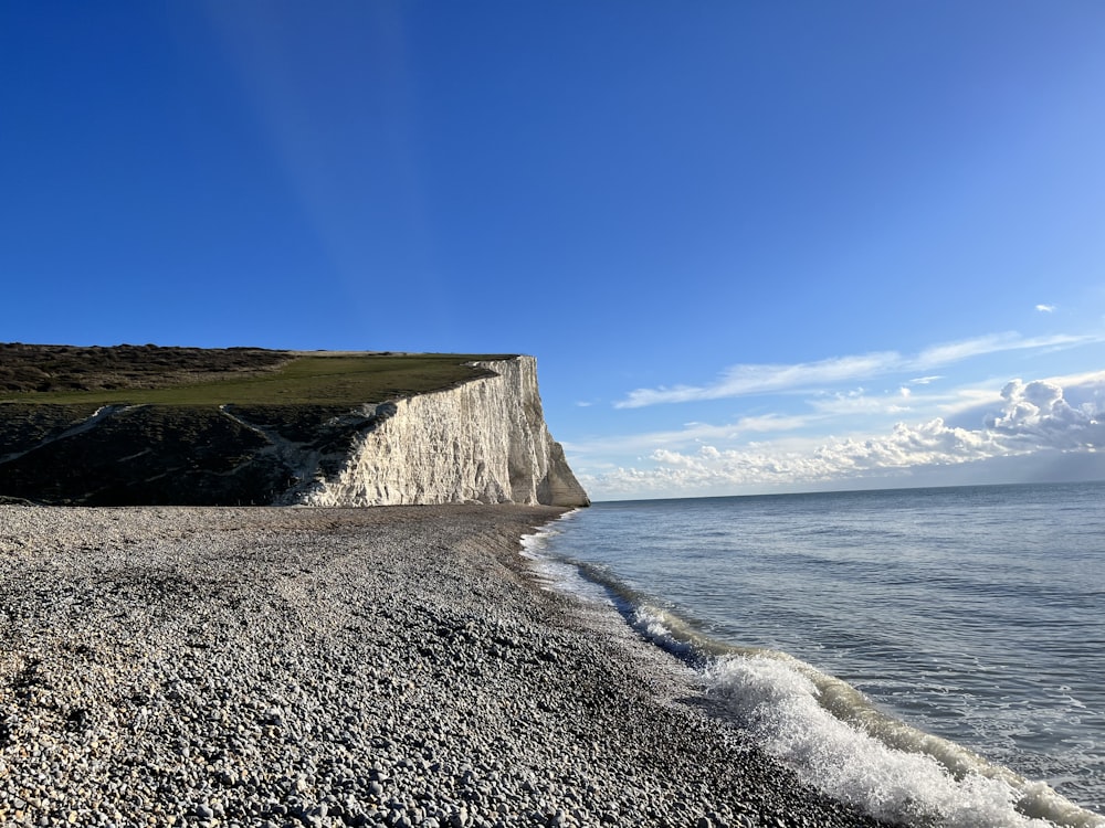 a view of a rocky beach with a cliff in the background