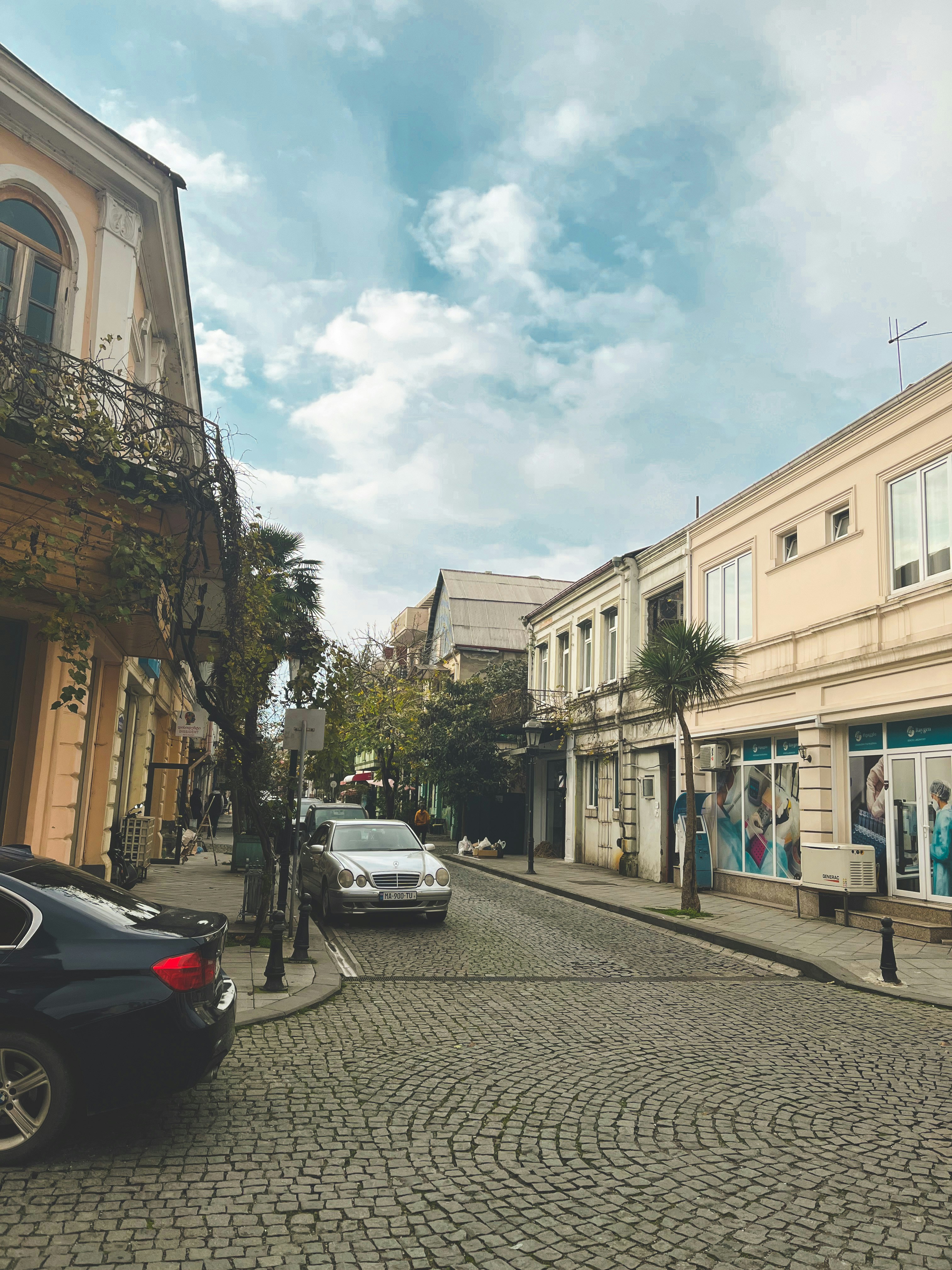 a cobblestone street with cars parked on both sides