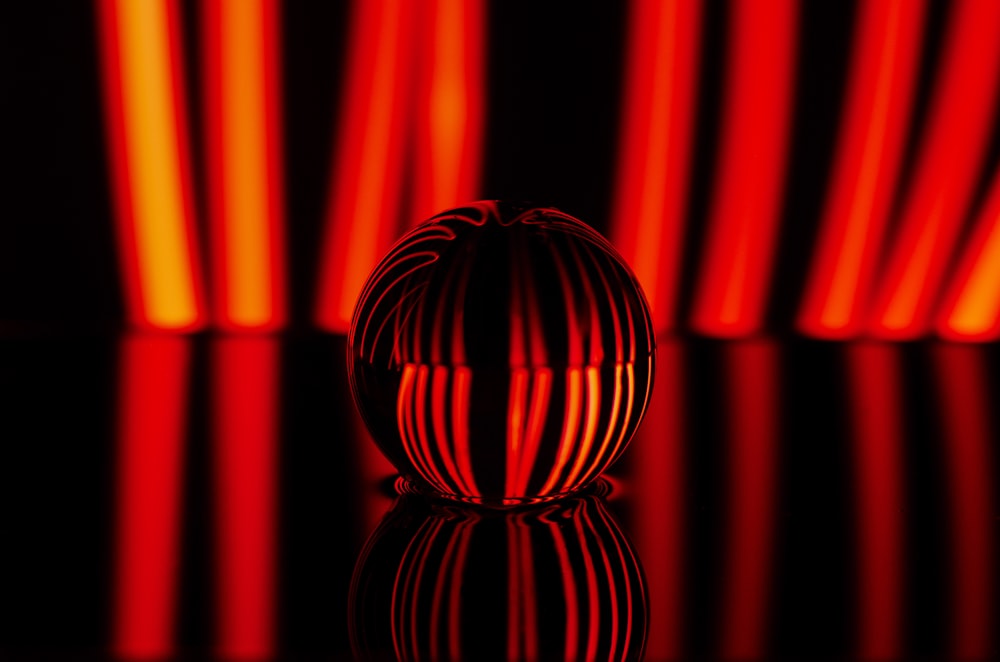 a red vase sitting on top of a reflective surface