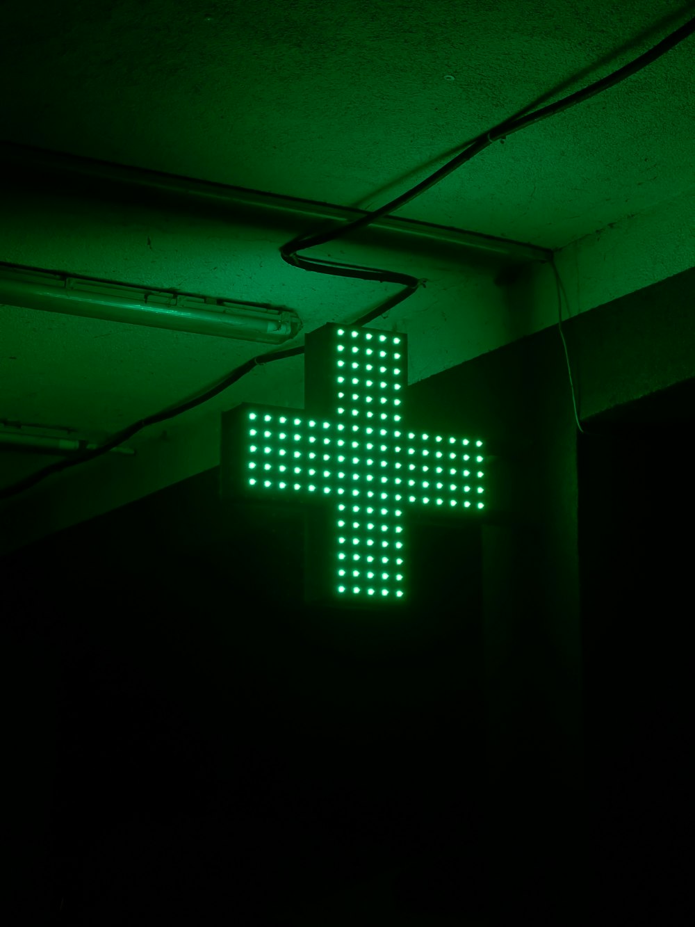 a cross made of green leds in a dark room