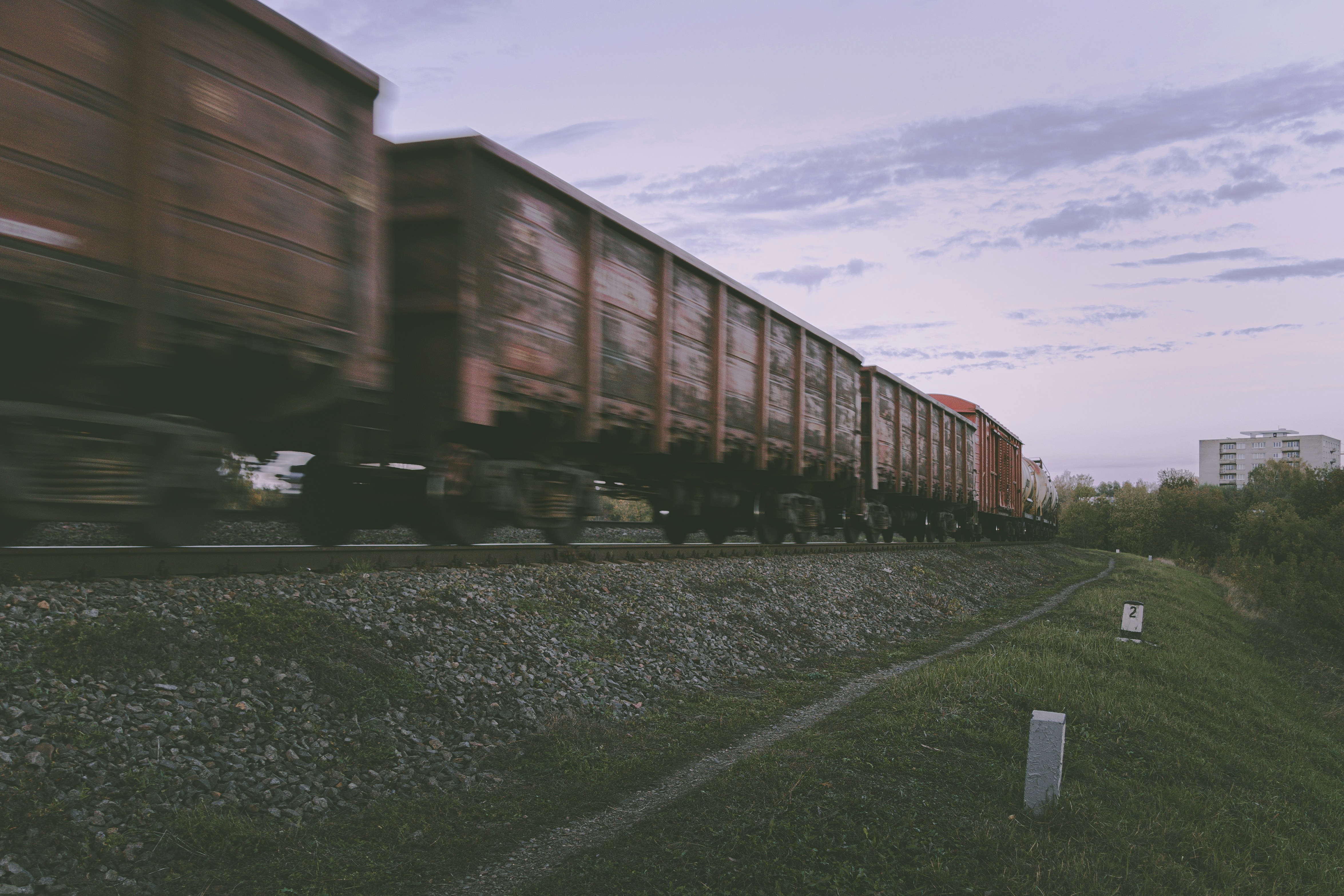 a train traveling down tracks next to a lush green field