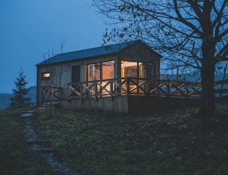 Cozy cabin exterior with warm lights glowing through the windows at dusk