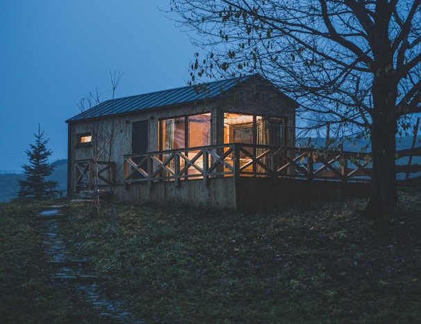 Cozy cabin exterior with warm lights glowing through the windows at dusk