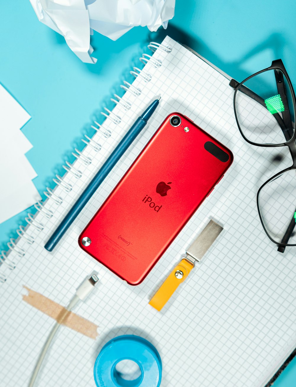 a red iphone sitting on top of a table next to a pair of glasses