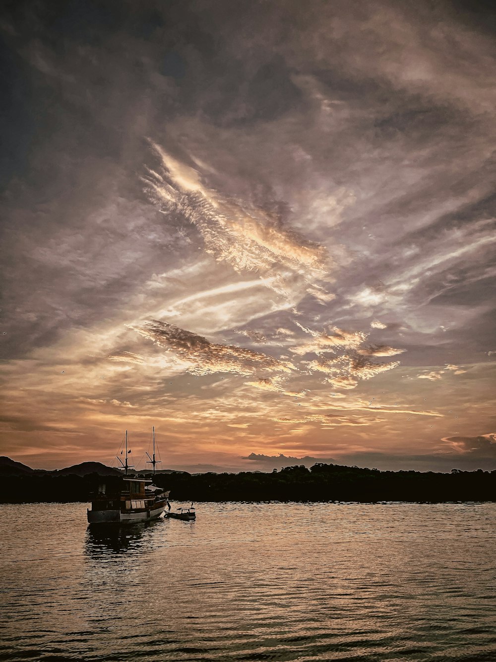 a boat floating on top of a lake under a cloudy sky