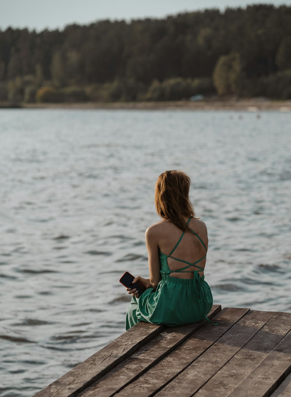 a woman sitting on a dock looking at the water