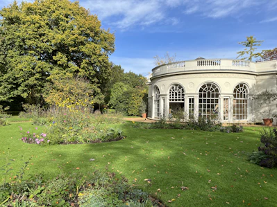 A well-maintained garden with vibrant flowers and trimmed bushes in front of a modern building.