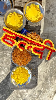 A rustic bowl filled with colorful hawan samagri ingredients beside a lit diya