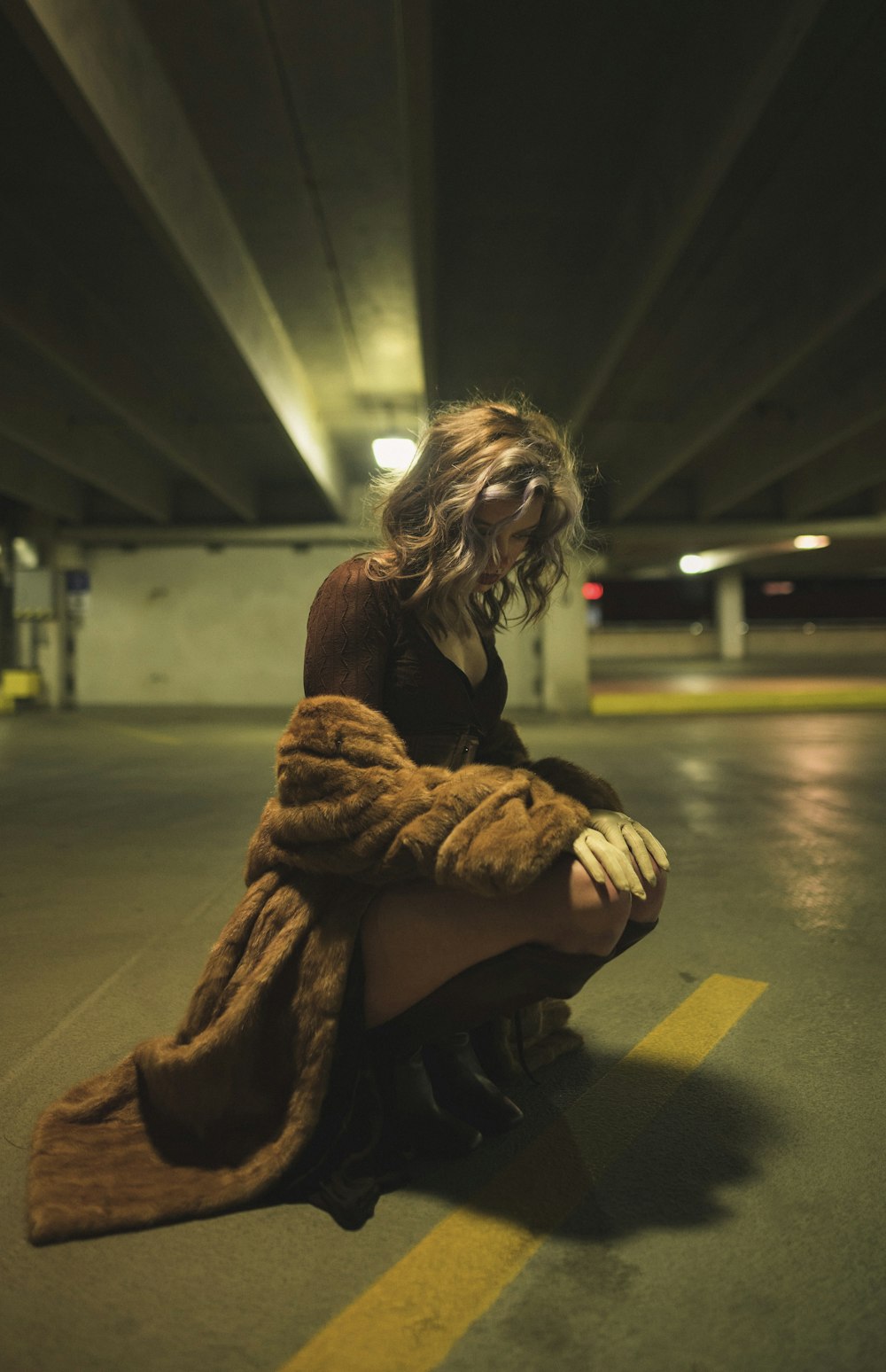 a woman sitting on the ground in a parking garage