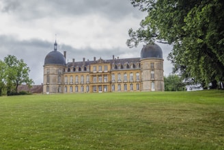 Elegant historic chateau surrounded by manicured lawns and tall trees.