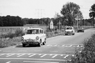 a black and white photo of cars driving down a road