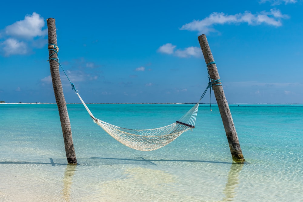a hammock hanging between two wooden poles in the ocean