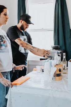 a man and a woman standing at a table with a coffee maker