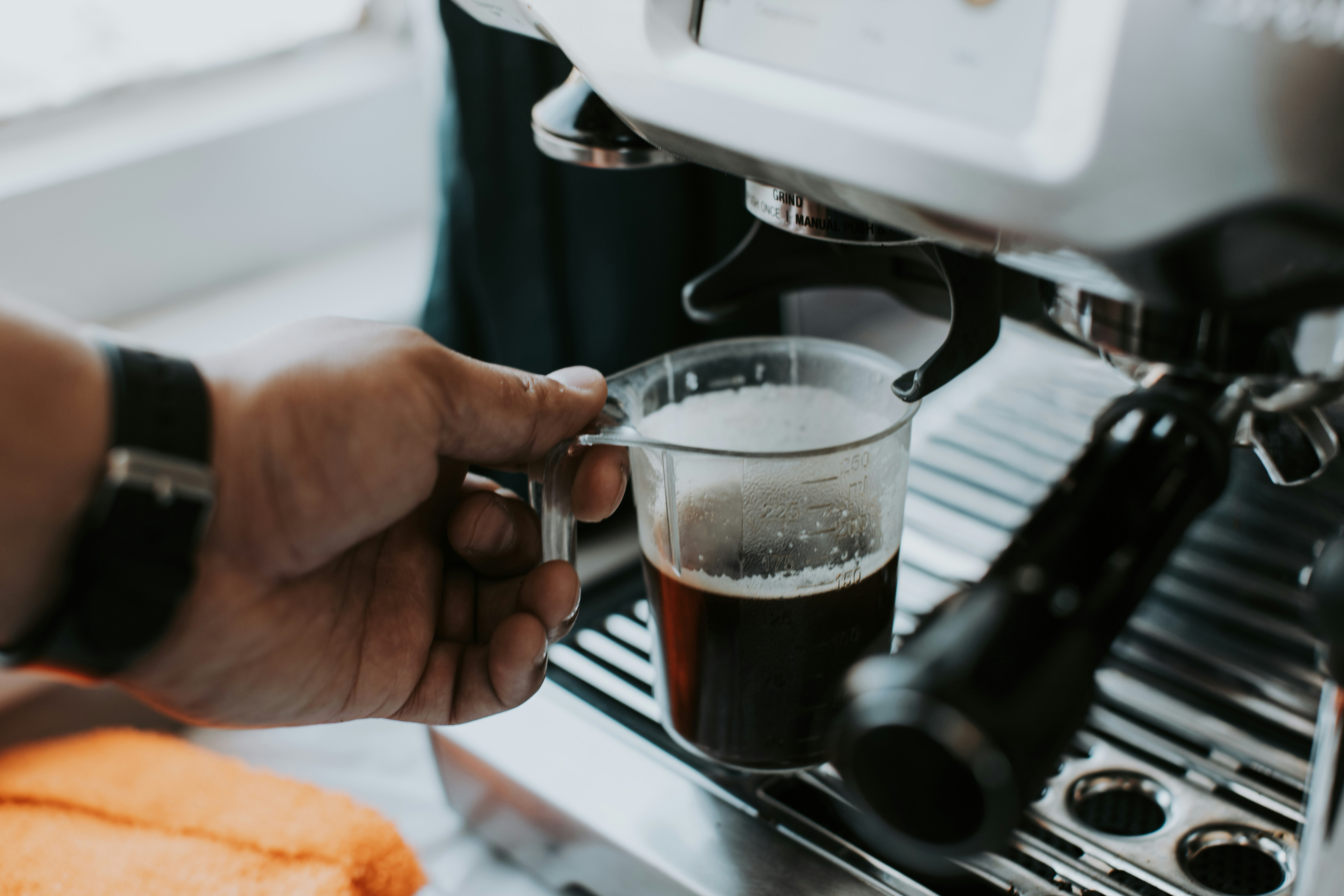 Person holding a glass of coffee at a machine