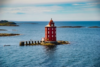 a red lighthouse on a small island in the middle of the ocean