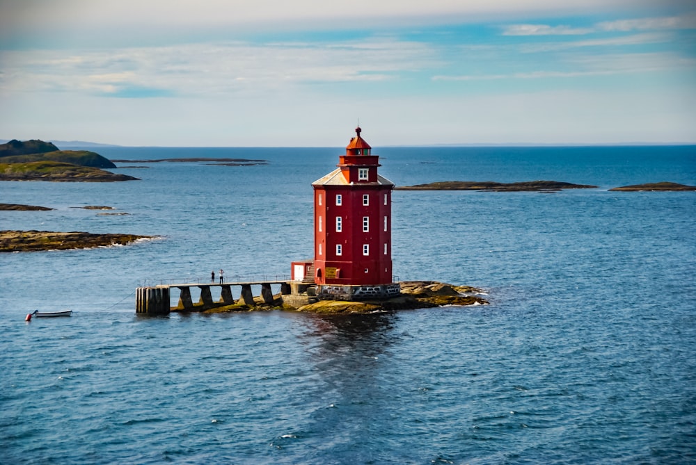 a red lighthouse on a small island in the middle of the ocean