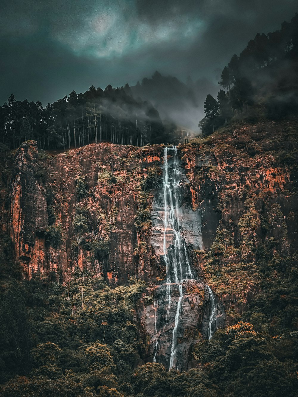 a very tall waterfall in the middle of a forest