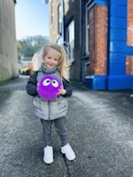 A child running outdoors while holding a colorful toy.