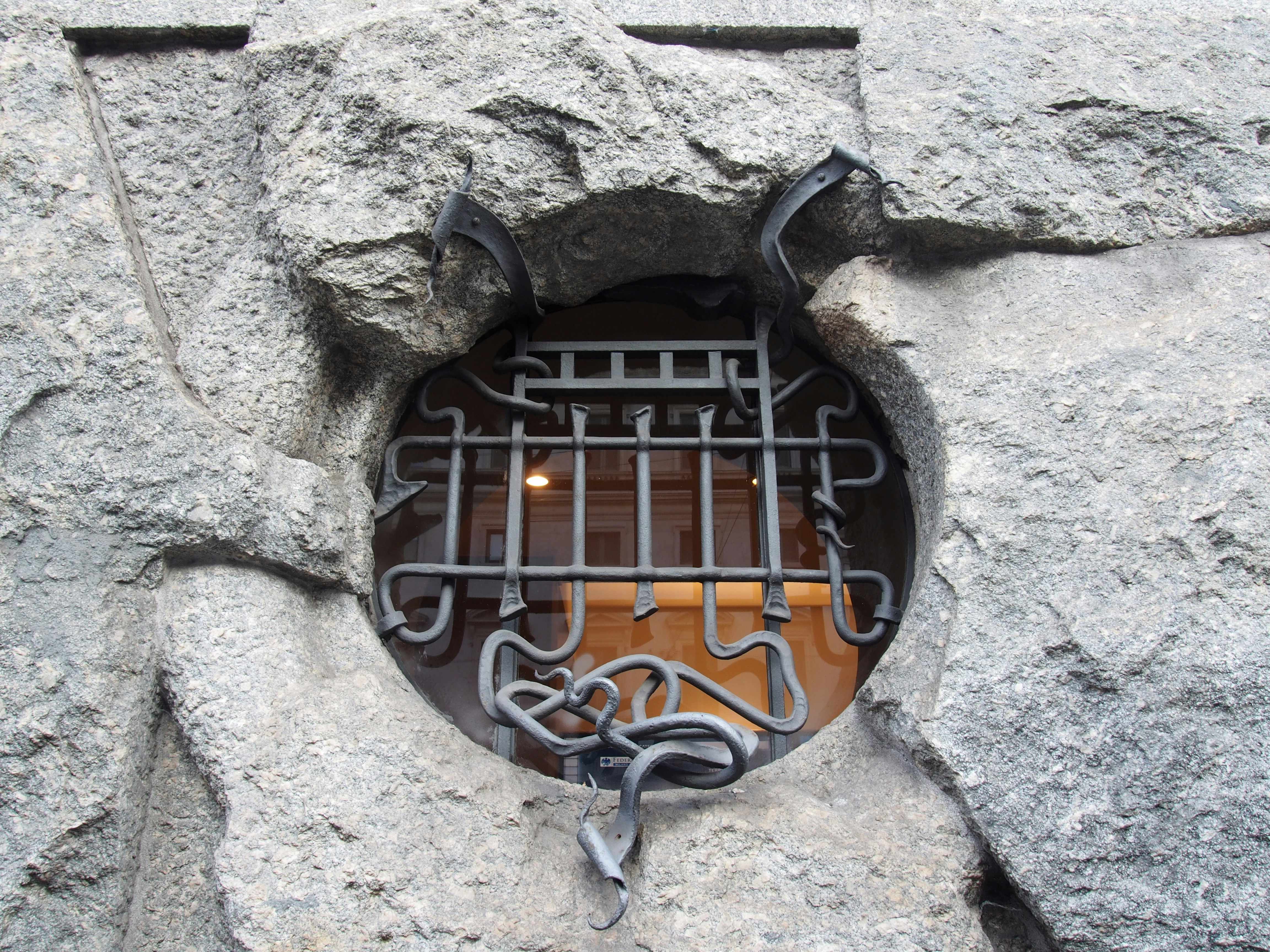 un trou dans le côté d’un mur de pierre avec une grille métallique à l’intérieur