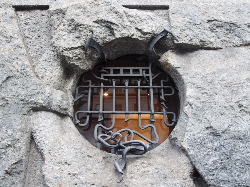 a hole in the side of a stone wall with a metal grate in it