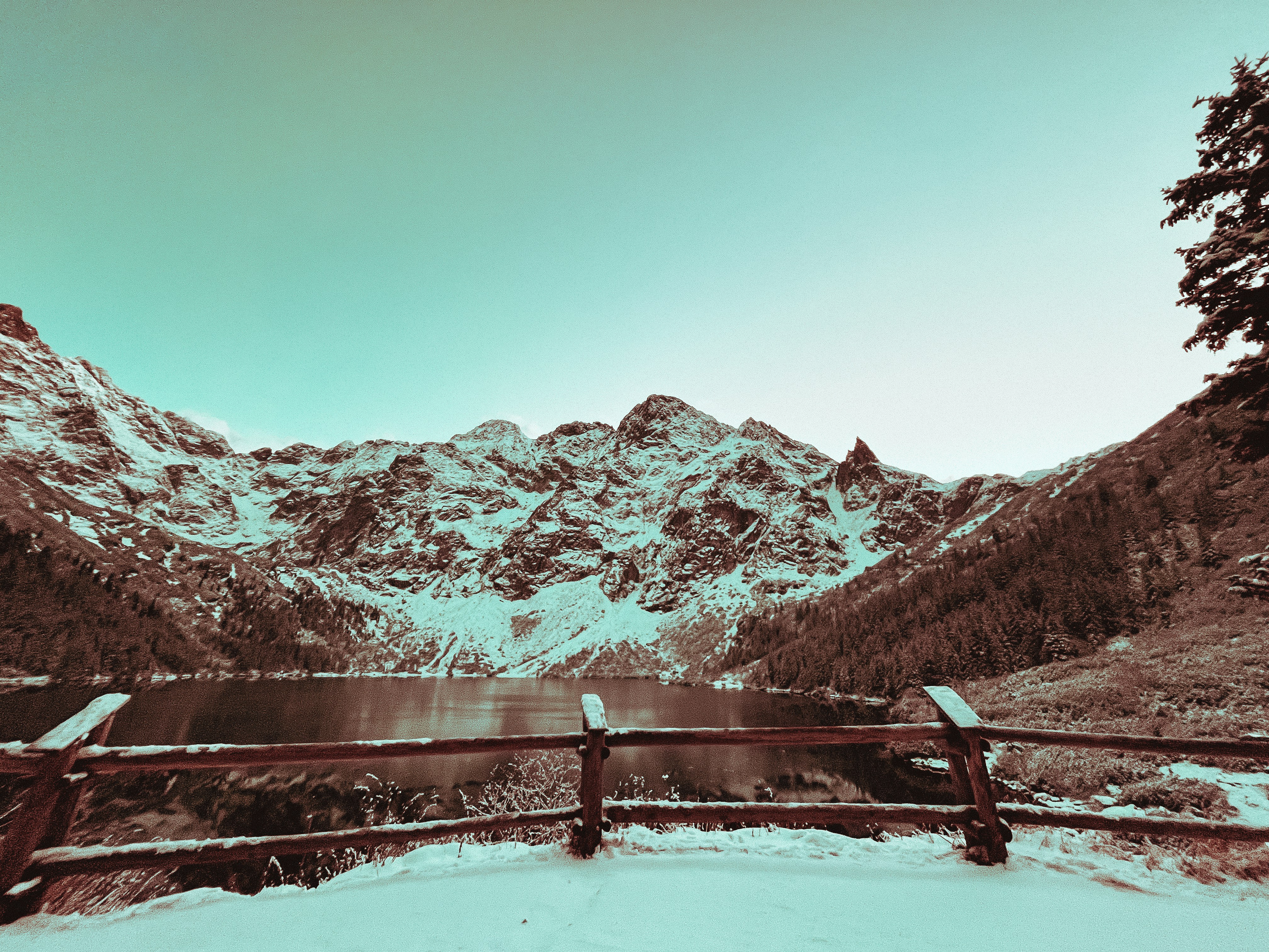 a snow covered mountain range with a lake in the foreground