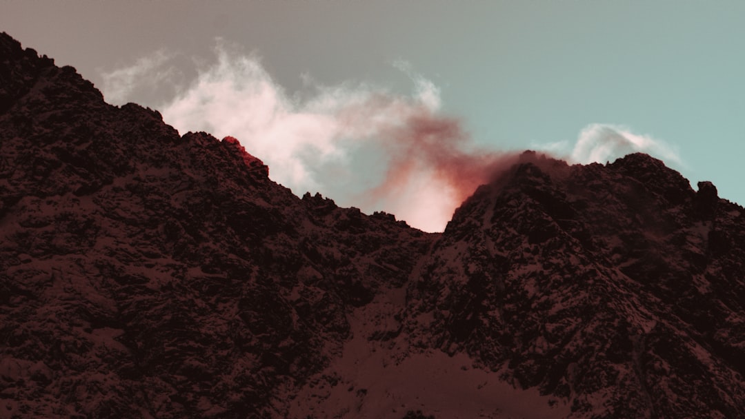 a very tall mountain with some clouds in the sky,