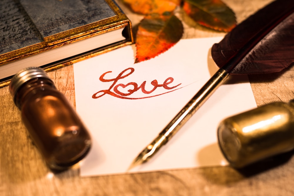 a note with the word love written on it next to a fountain pen