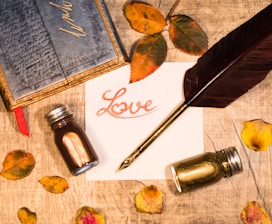 a note with a pen, ink bottle, and inkwell sitting on a table