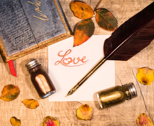 a note with a pen, ink bottle, and inkwell sitting on a table