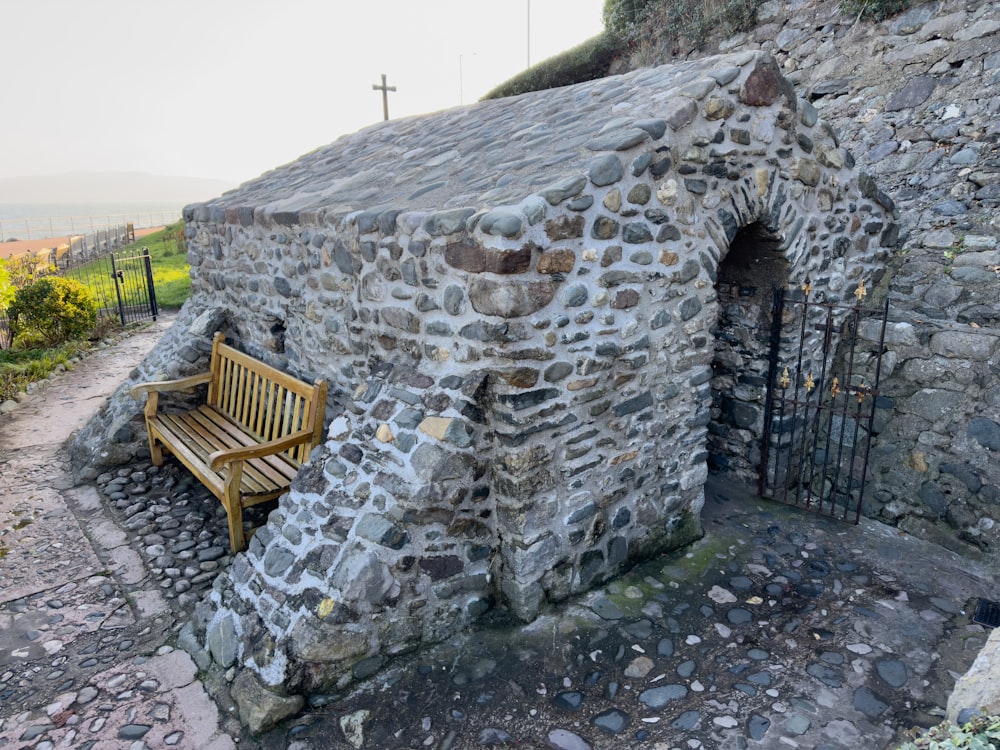 a wooden bench sitting next to a stone building