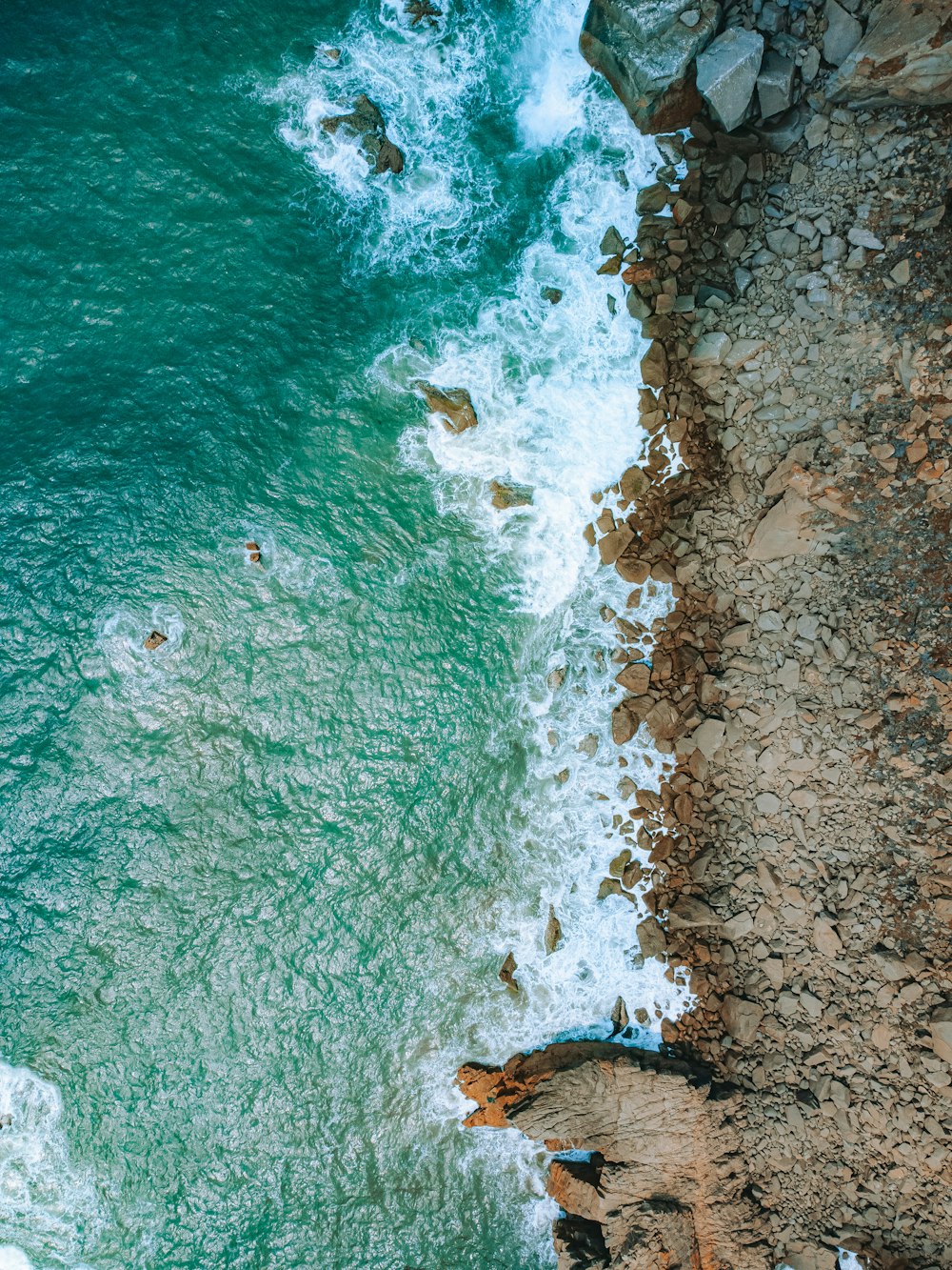 an aerial view of a beach with people swimming in the water