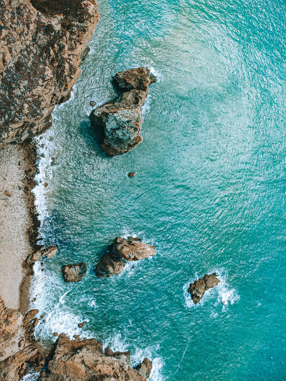 an aerial view of the ocean and rocks