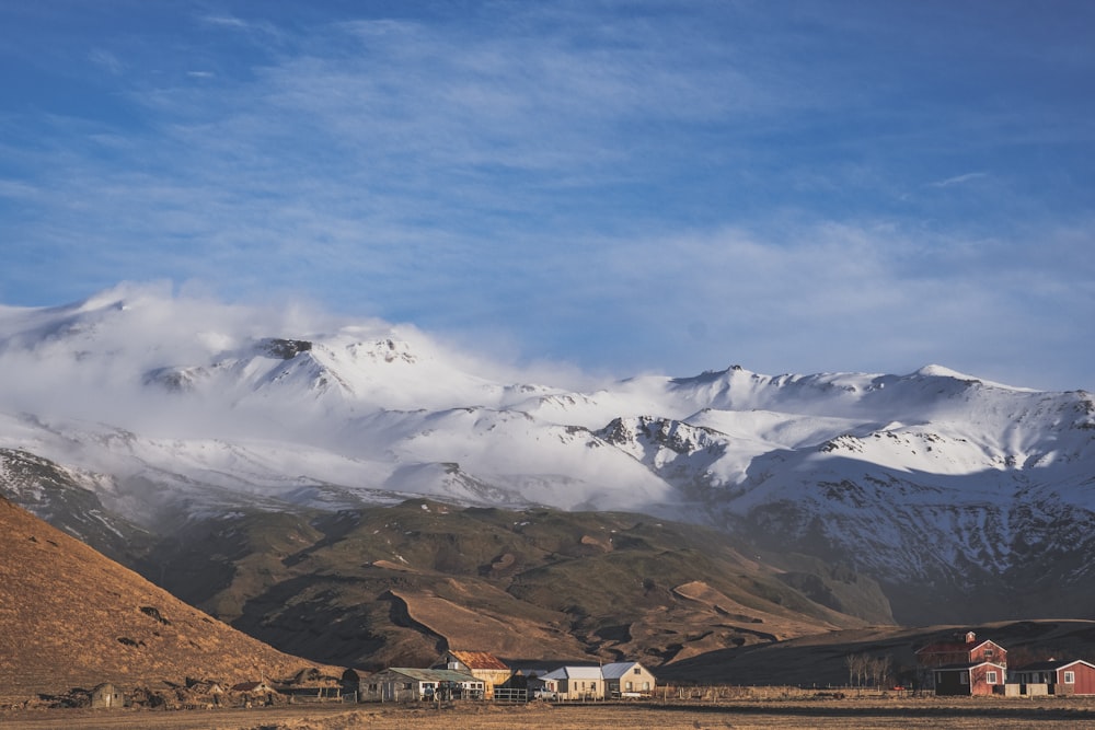 a snowy mountain range with houses in the foreground