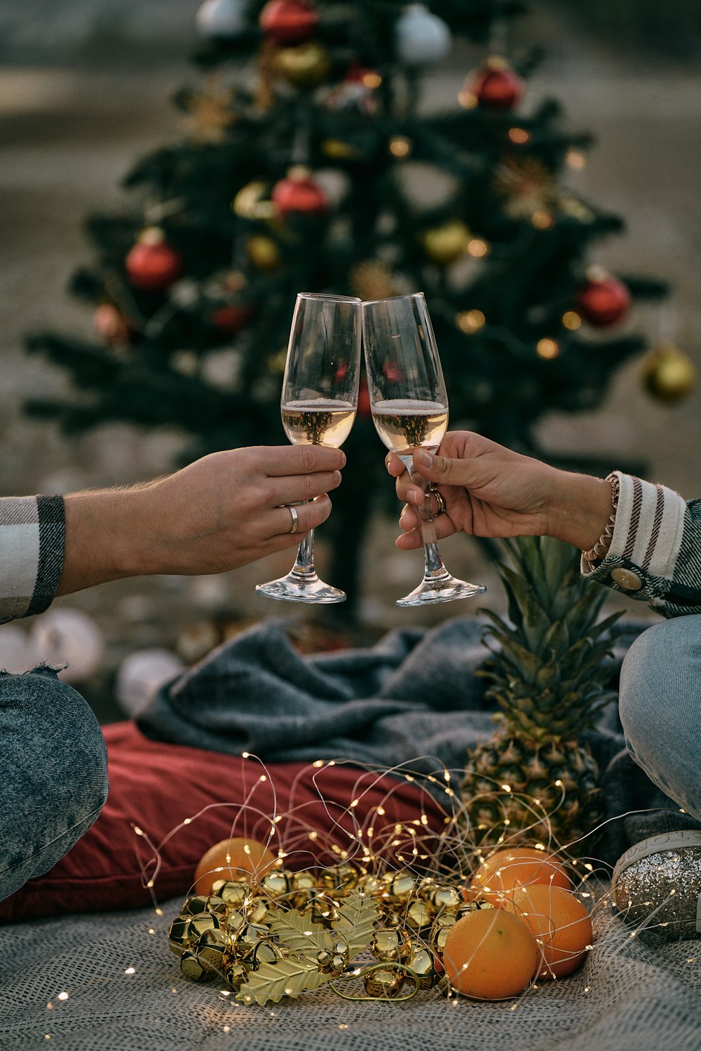 two people toasting with wine glasses in front of a christmas tree