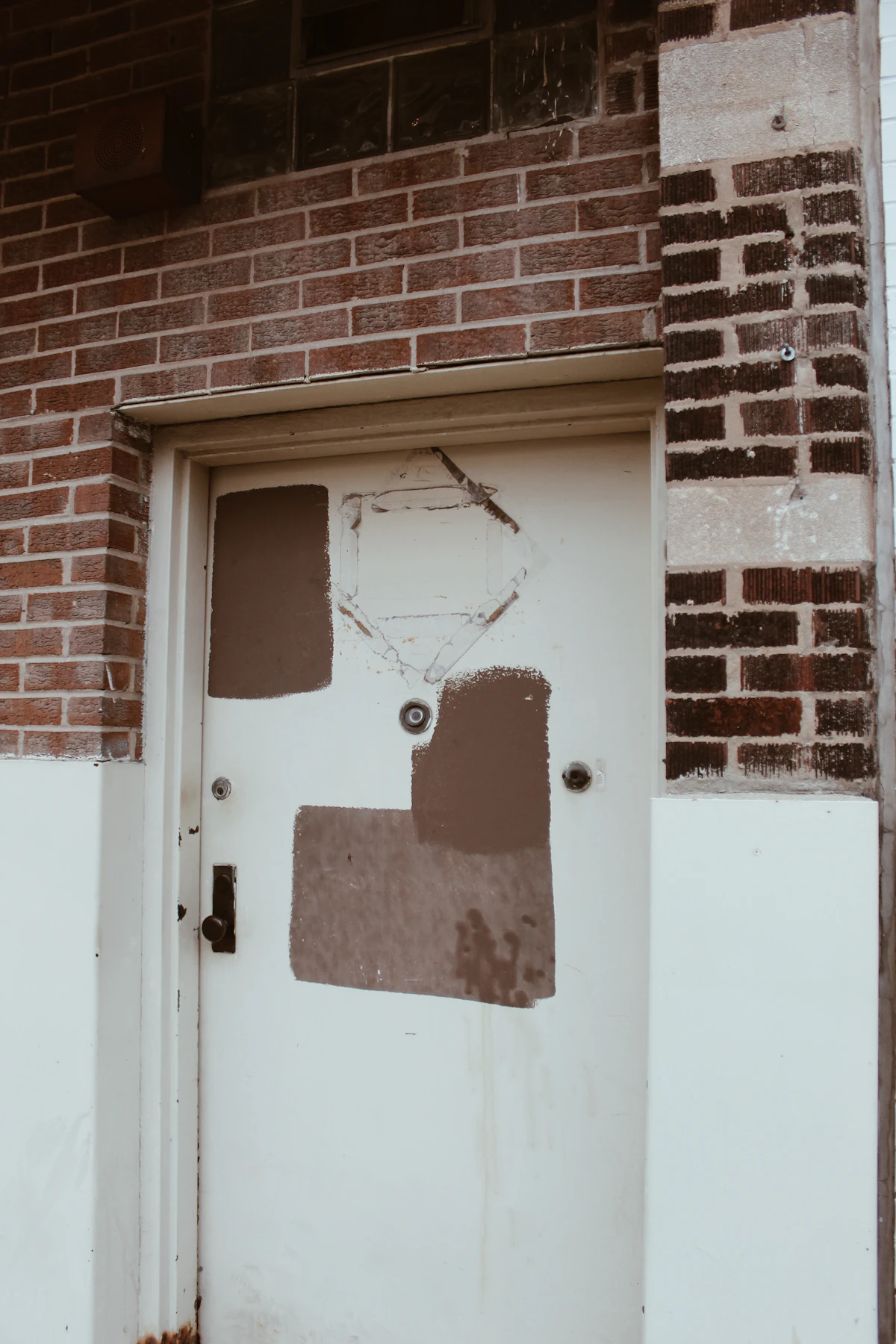 Porte d'entrée blanche neuve sur une façade en briques