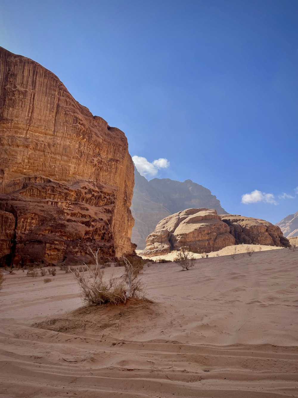 a desert area with a rock formation and mountains in the background