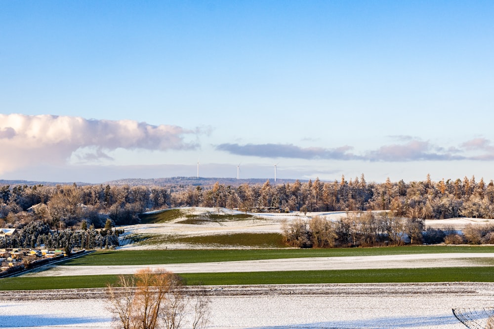 a snow covered field with a wind turbine in the distance