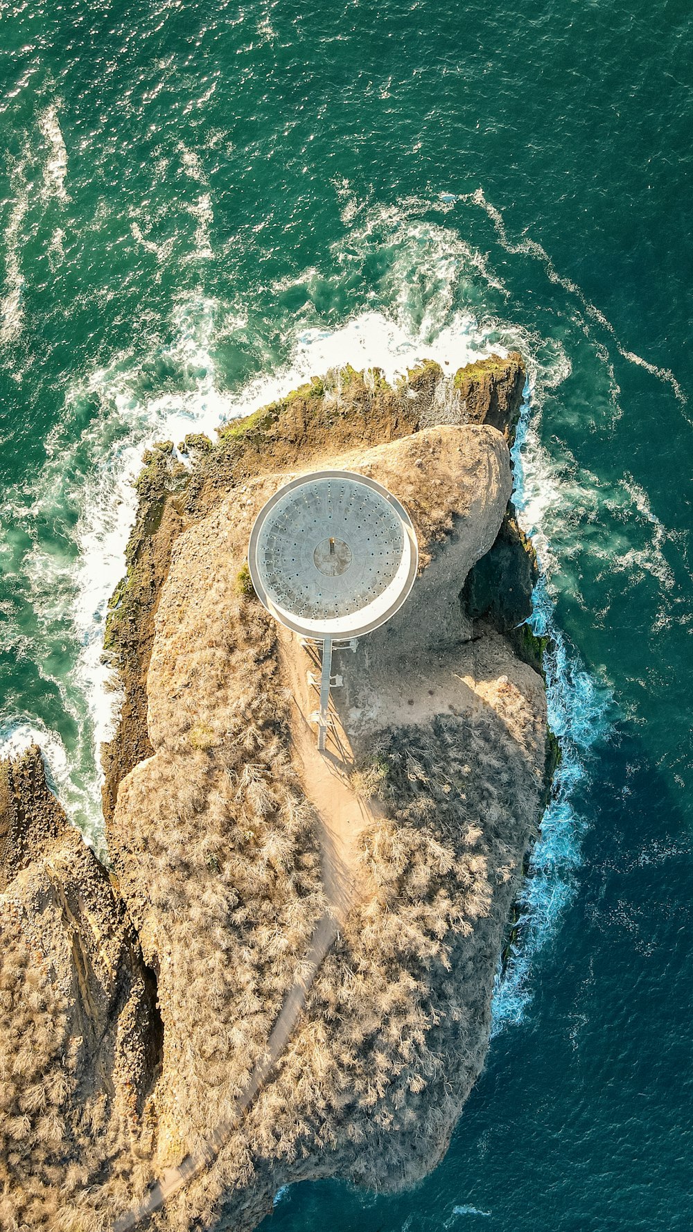 a satellite dish sitting on top of a rock in the ocean