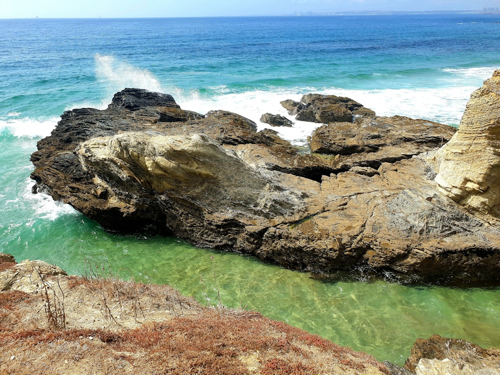 a rock formation in the water near a beach