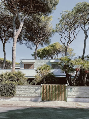 a house with trees and a fence in front of it