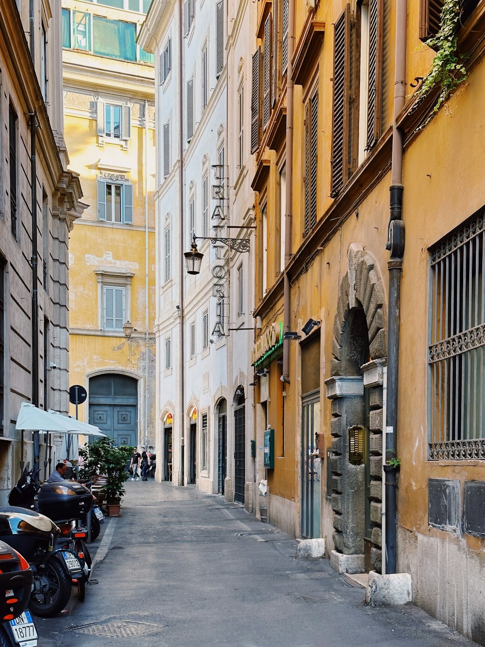 a narrow city street lined with parked motorcycles