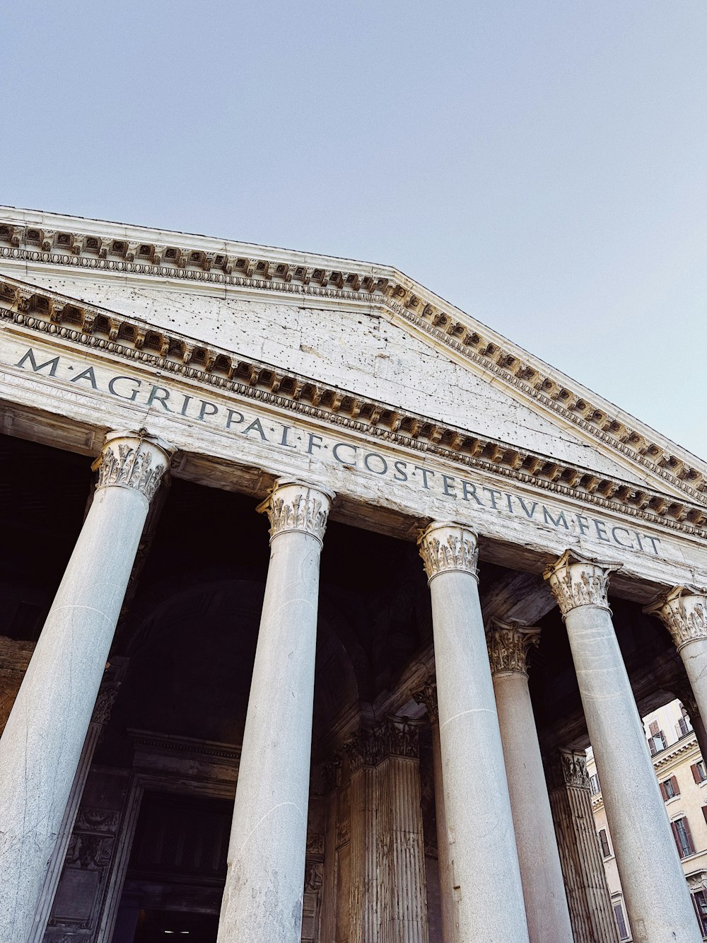 a large building with columns and a clock on the side of it