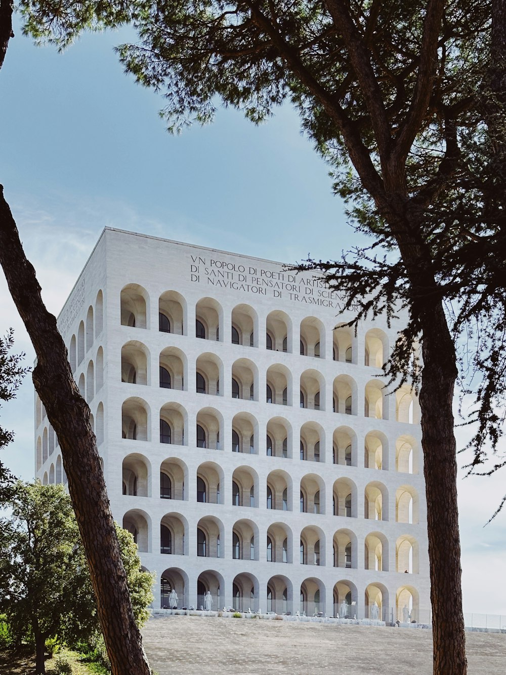 a large white building surrounded by trees on a sunny day